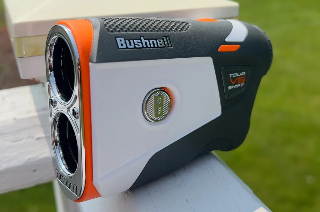 Bushnell Tour V6 Shift Laser Rangefinder closeup sitting on a white wooden handrail.