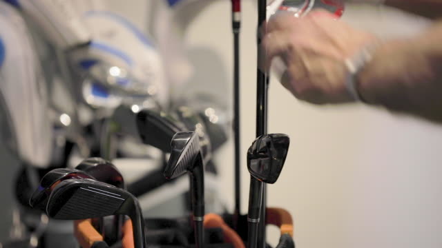 A man pulls a golf club out of the golf bag to play on a virtual driving range.