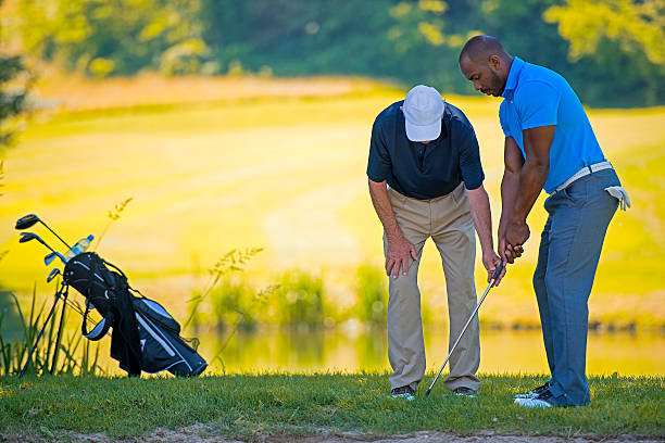 Golf pro teaching beginner golfer on driving range.