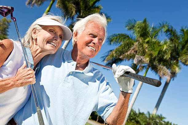 Happy senior man and woman couple together playing golf putting on a green together