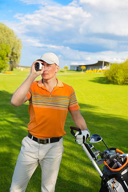 man golfer watching into rangefinder at his hit