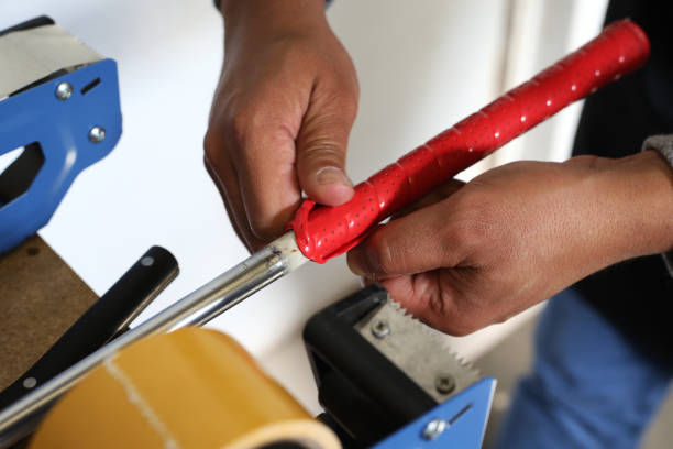 A Golf Club Builder removes an old grip from a golf club.